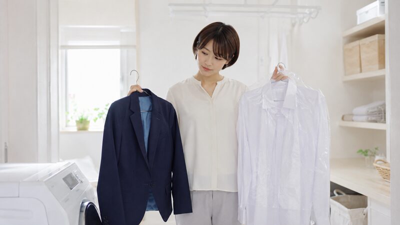クリーニング前に洗濯が必要か悩みながら衣類を確認する日本人女性